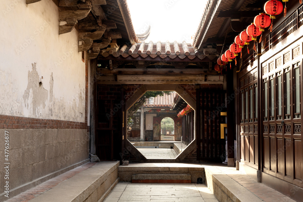 Chinese moon gate with a view of Chinese temple, red lanterns under the eaves. Chinese moon gate with a view of Chinese temple, red lanterns under the eaves.