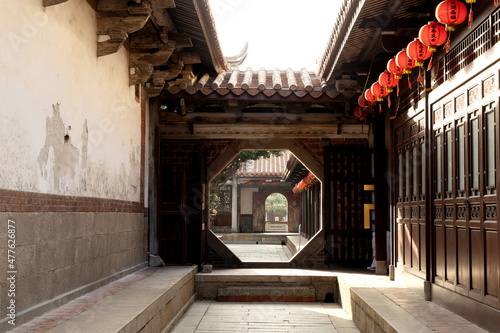 Chinese moon gate with a view of Chinese temple, red lanterns under the eaves.