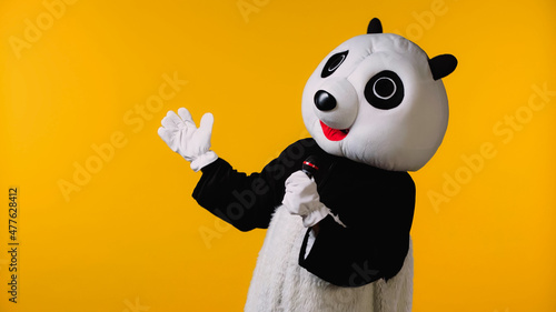 person in happy panda bear costume talking in microphone isolated on yellow. photo