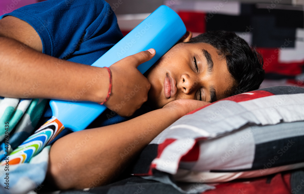 Teenager kid sleeping by holding cricket bat - concept of childhood dream of becoming cricketer, player, and objective. Teenager kid sleeping by holding cricket bat - concept of childhood dream of becoming cricketer, player, and objective.