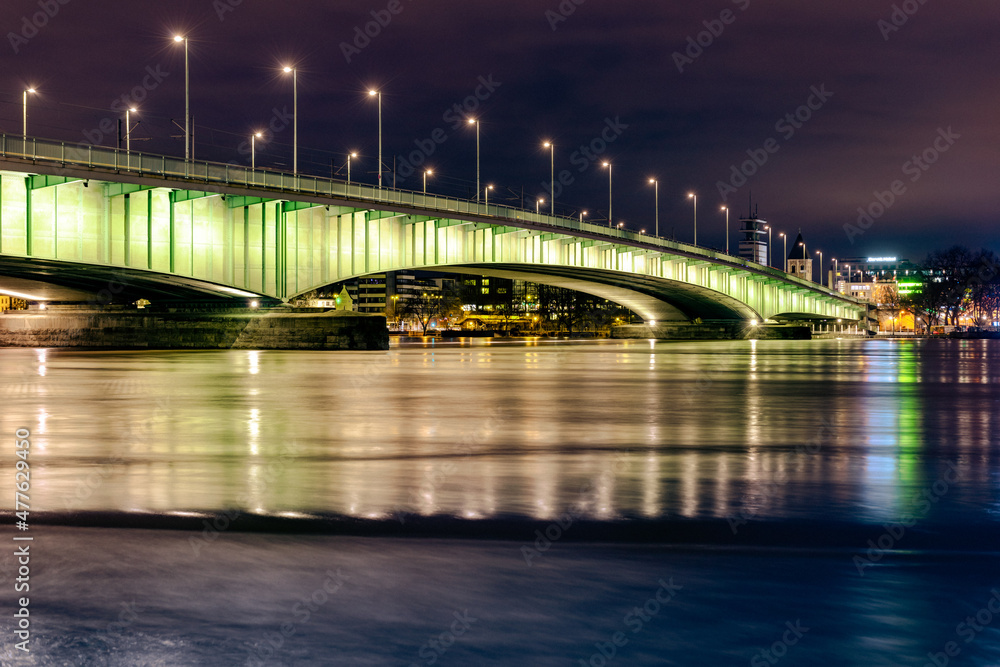 The illuminated Deutz Bridge over the moving river Rhine at Cologne night. The illuminated Deutz Bridge over the moving river Rhine at Cologne night.