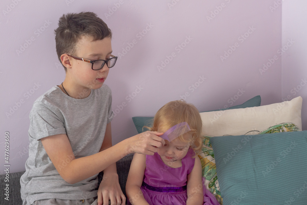 Brother combs his younger sister's hair with a comb