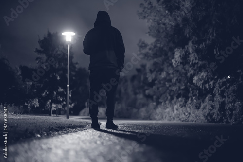 Hooded man walking alone in dark streets