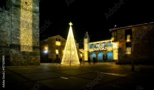 People walking and enjoying the Christmas lights in the medieval old town of Puebla de Sanabria. Zamora. Spain. Luminous text saying Merry Christmas. 