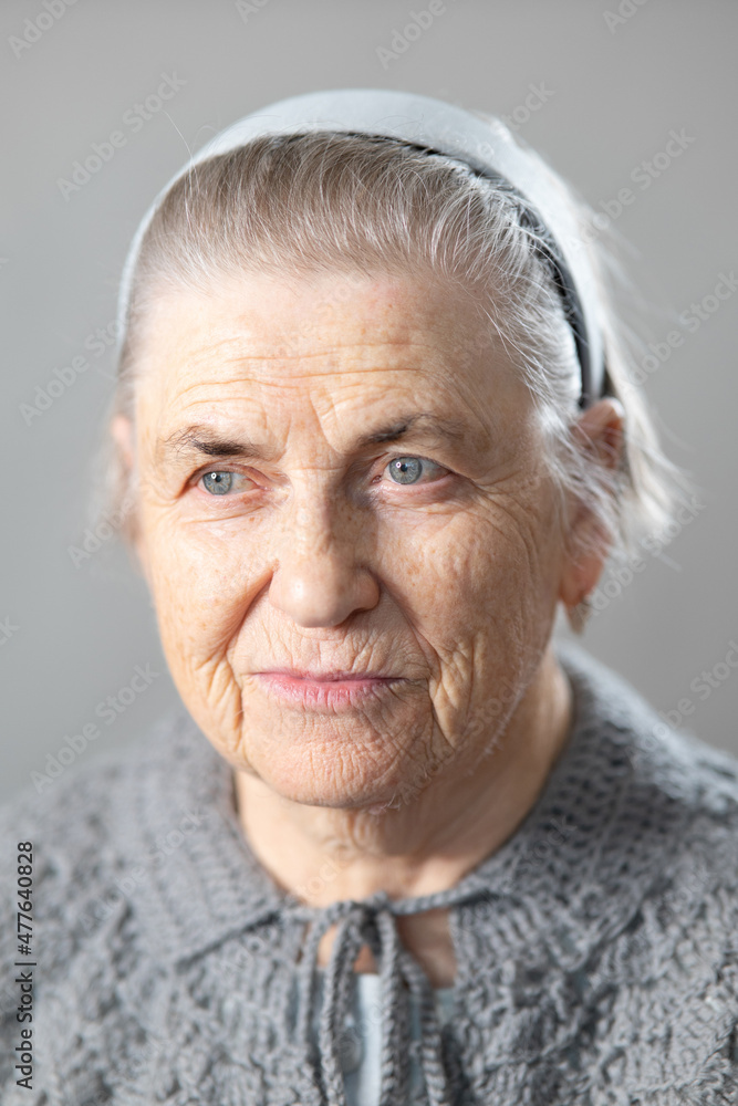 Close-up of an elderly woman's face with deep wrinkles. Portrait of an old  lady of seventy with gray hair in a knitted jacket. Stock Photo | Adobe  Stock