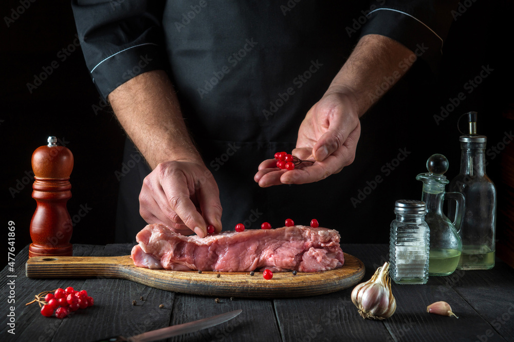 Professional chef prepares raw veal meat. Before baking, the cook puts the viburnum on the beef. National dish is being prepared in the restaurant kitchen.
