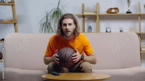 focused sport fan watching basketball match on tv at home. photo