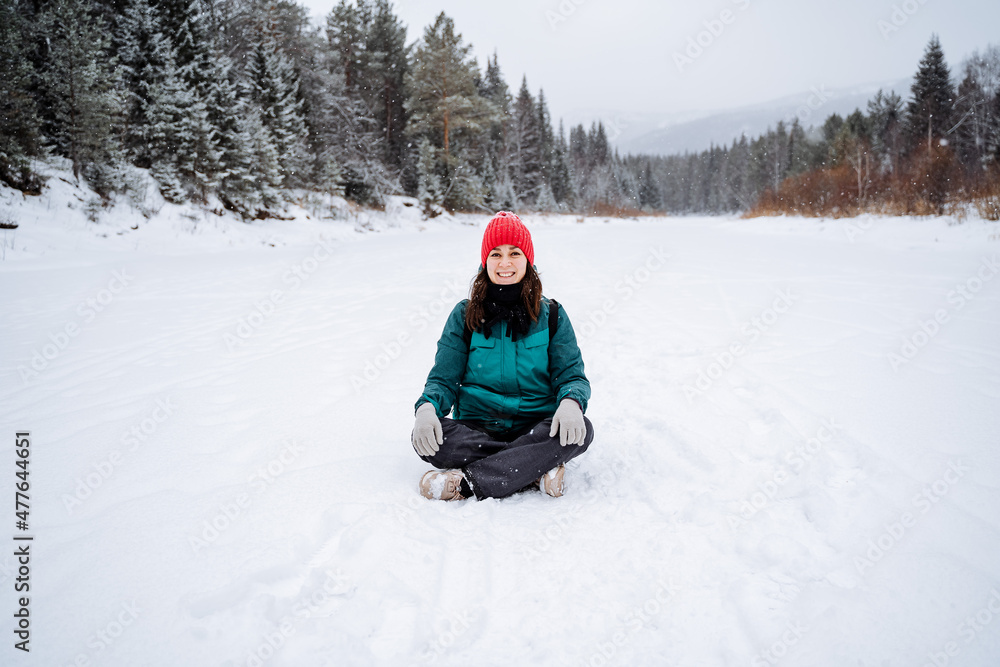 A cheerful girl meditates in a snowy valley. a woman sat down to rest in the snow. A walk in the forest in winter, filled with peace, tranquility and joy