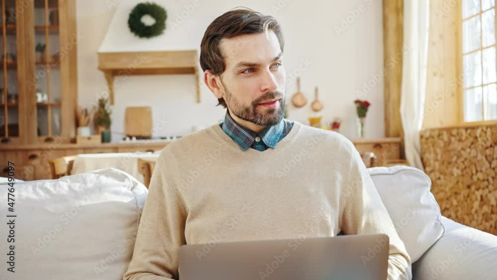 Close up portrait of young thoughtful bearded businessman working on laptop at home, thinking about problem solution Close up portrait of young thoughtful bearded businessman working on laptop at home, thinking about problem solution