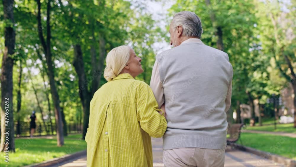 Joyful man and woman smiling to each other, walking in city park, romantic date Joyful man and woman smiling to each other, walking in city park, romantic date