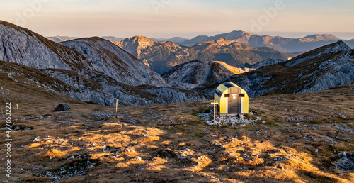 View of green tent and Fleischer-Biwak in evening light near Schiestlhaus hut, sunny weather, sunset, blue sky. Autumn vibes in mountain range Hochschwab, Styria, Austrian Alps, Europe. photo