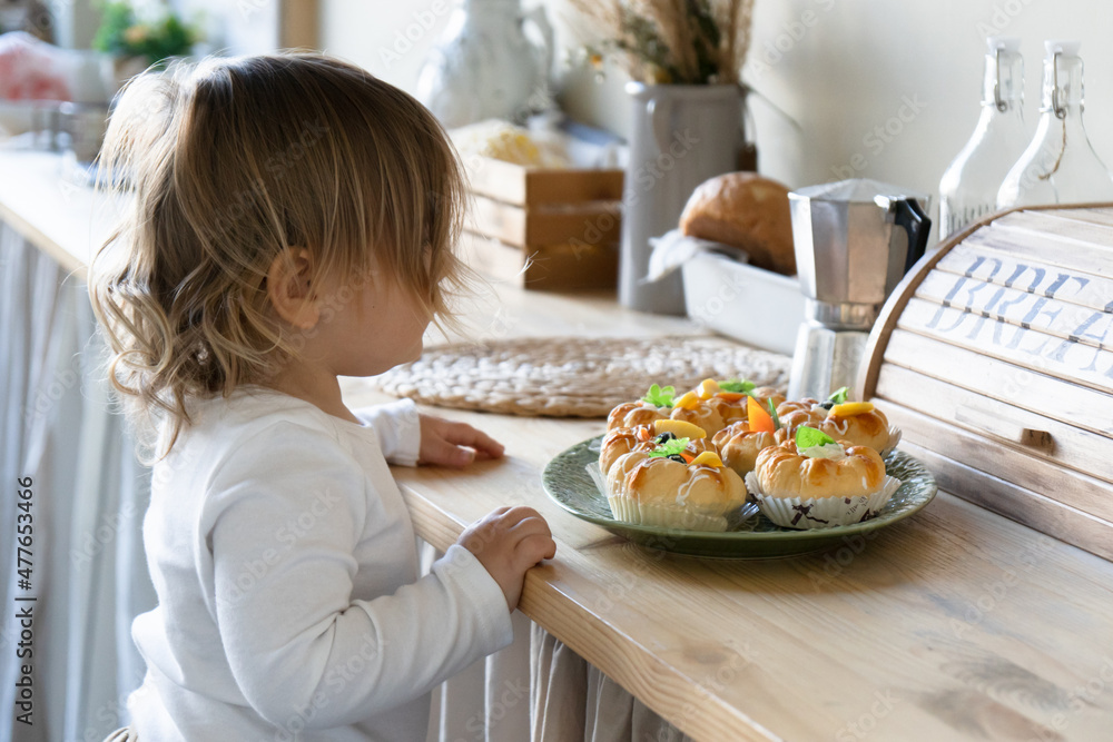 The baby looks at fresh cakes with curiosity .Children's independence and help. Montessori kindergarten, lifestyle photo .Candid. Soft focus
