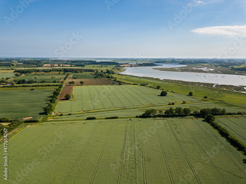 Aerial view of a patchwork of farm fields in the Suffolk countryside with the River Deben in the distance