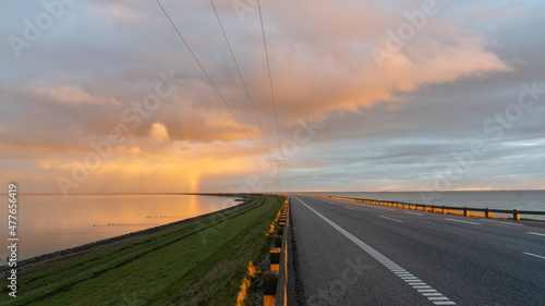 Fotografie, Obraz Slow travel Denmark: Sunlit thunderclouds and a bright rainbow on the far end of