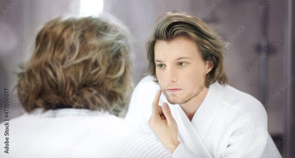 young man looking in the mirror,combing his hair,looking at problems on face. young man looking in the mirror,combing his hair,looking at problems on face.