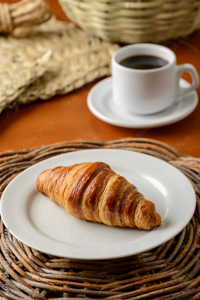 Croissant on white plate for breakfast.