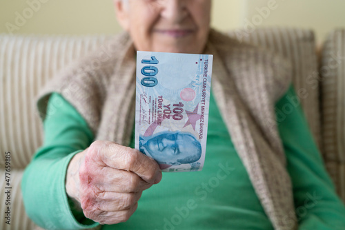 closeup wrinkled hands of old person holding money, Turkish lira banknotes photo