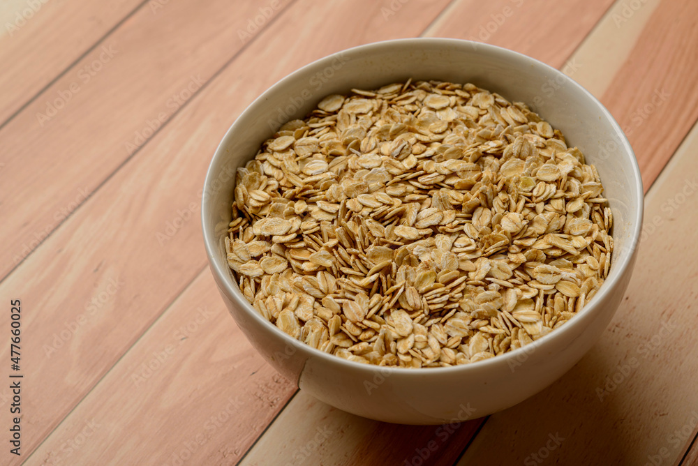 Oatmeal in white bowl on wooden table. Oatmeal in white bowl on wooden table.