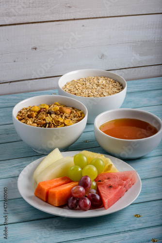 Fruits, honey, oats and granola on blue wooden table. Healthy food.