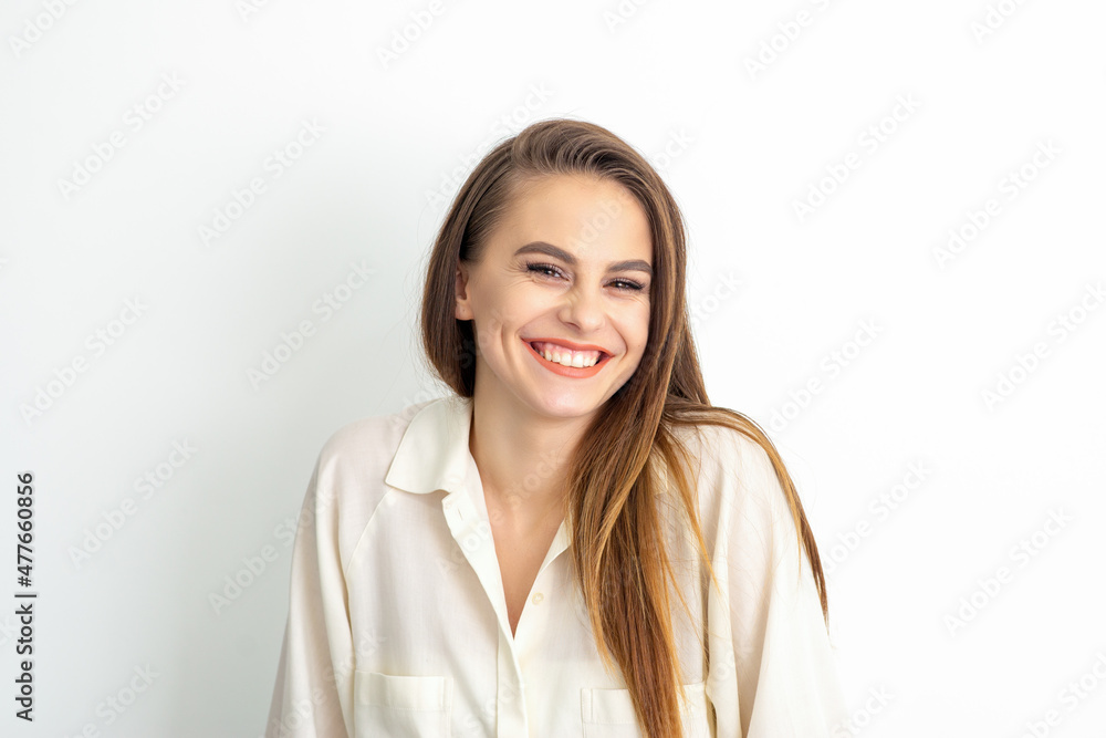 Beauty concept of woman. Portrait of a happy charming shy smiling young caucasian woman with long brown hair posing and looking at the camera over white background Beauty concept of woman. Portrait of a happy charming shy smiling young caucasian woman with long brown hair posing and looking at the camera over white background