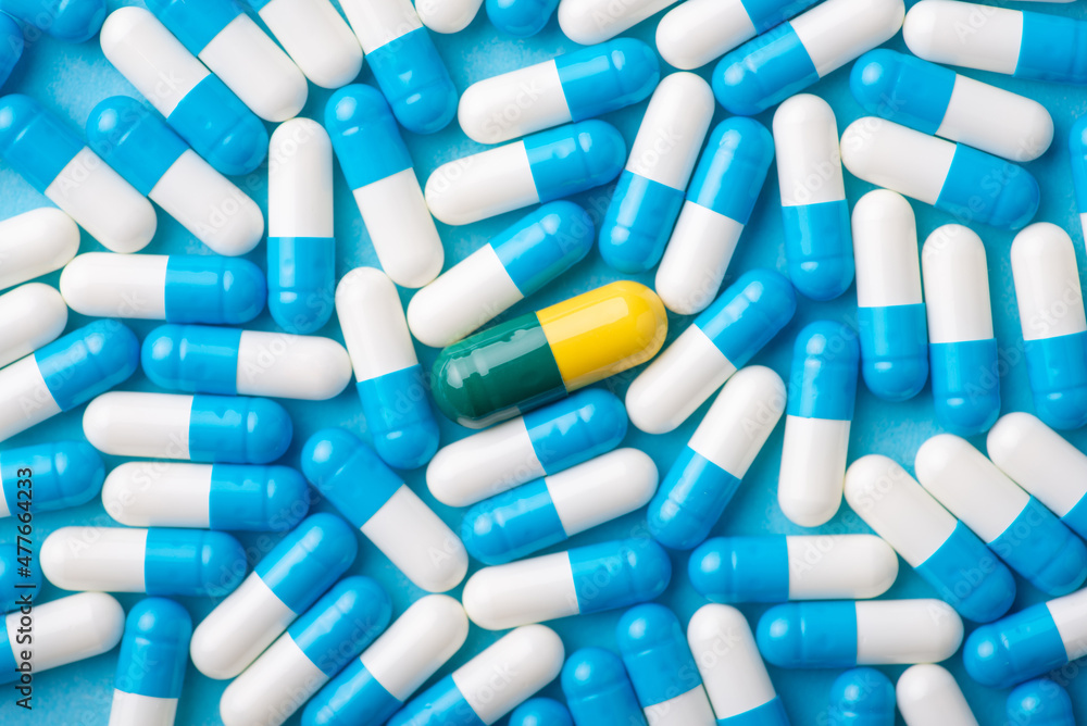 Many blue and white pills with one different in the middle. Treatment, medicine concept Many blue and white pills with one different in the middle. Treatment, medicine concept