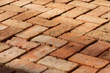 Antique salvaged reclaimed red bricks used for making patern floor. Daylight shadows low angle view closeup details.