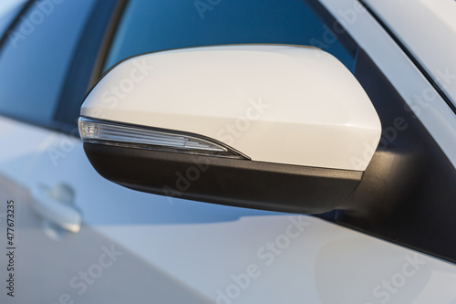 Side mirror of a modern car. The elements of the car body are white.