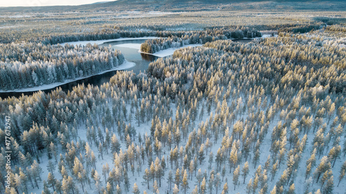 Aerial view of snowy winter forest with black river. Drone photography - panoramic image of beautiful frosty trees and loops of river in Jamtland County, Sweden photo