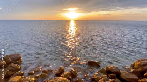 The sea in the evening with yellow rocks and blue water, with the sun shining down in golden yellow, represents the sunset or the sunrise, can be used in marine and nature related work.