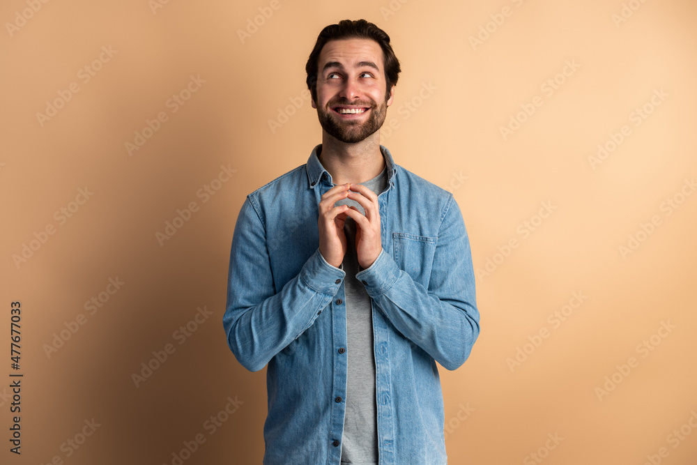 Fototapeta premium Caucasian man isolated over orange background clenches fingers and awaits for something