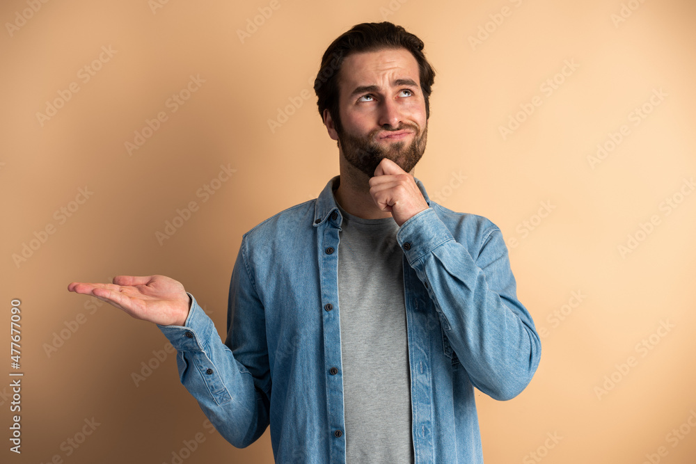 Portrait of young pensive man with beard touching chin and thinking about important question Portrait of young pensive man with beard touching chin and thinking about important question