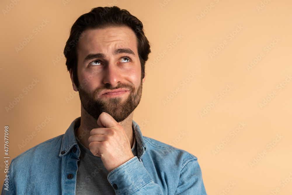 Thoughtful brunette man with beard holding his chin and pondering idea, confused about solution Thoughtful brunette man with beard holding his chin and pondering idea, confused about solution