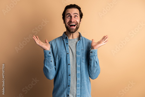 Excited shocked man holding hands near face and screaming looking up with big eyes