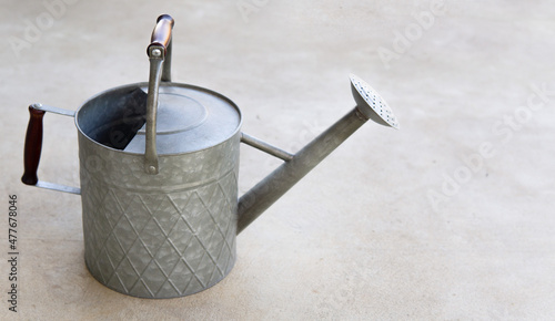 A Traditional metal watering can sitting on the patio