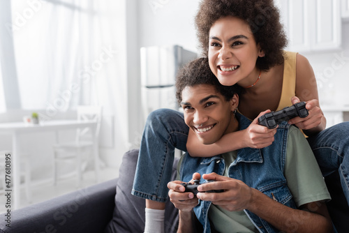 KYIV, UKRAINE - NOVEMBER 9, 2021: Focused african american woman playing video game with boyfriend at home.