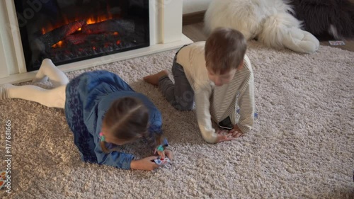 Childhood, education, isolation. Relaxing resting at home. Three little smart preschool children playing cards on carpet floor fireplace. Kids brother sister friends have interest in gambling games