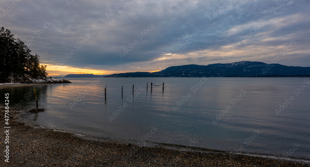 Snowfall in the San Juan Islands of the Pacific Northwest. A somewhat rare snow event blankets the beaches and mountains during a wintry sunset of western Washington state.