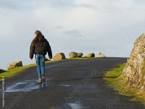 Obraz na plátně Young teenager girl walking uphill on a small asphalt twisted road in a mountains
