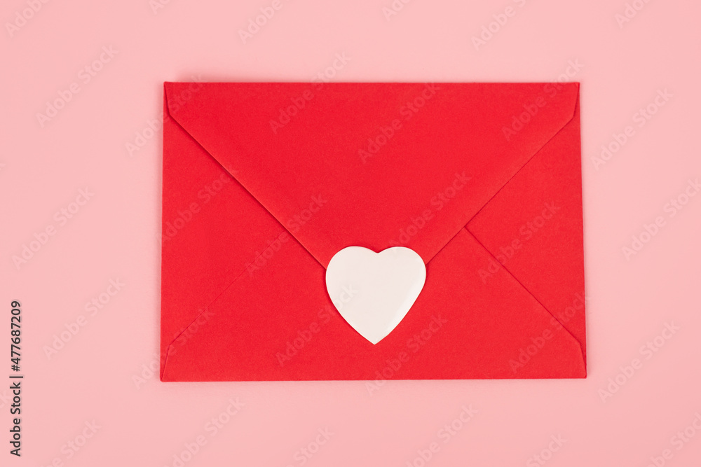 top view of paper heart sticker on red envelope isolated on pink.