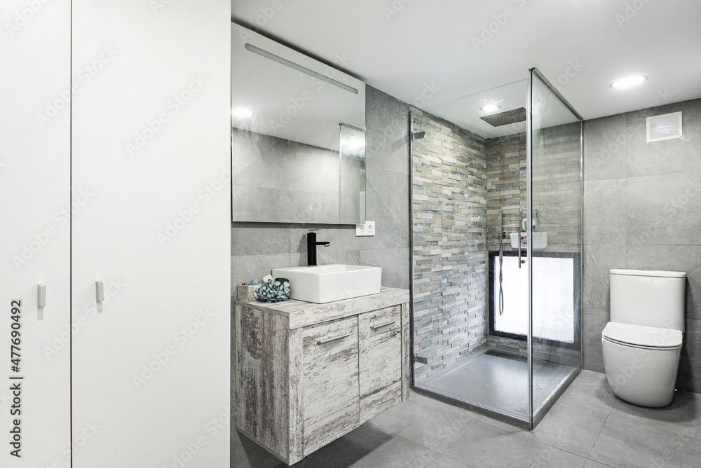 Toilet with white cabinet, porcelain sink and glass pane shower cubicle