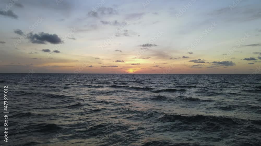 Low ocean aerial: Colorful golden sunrise over wavy sea to horizon Low ocean aerial: Colorful golden sunrise over wavy sea to horizon