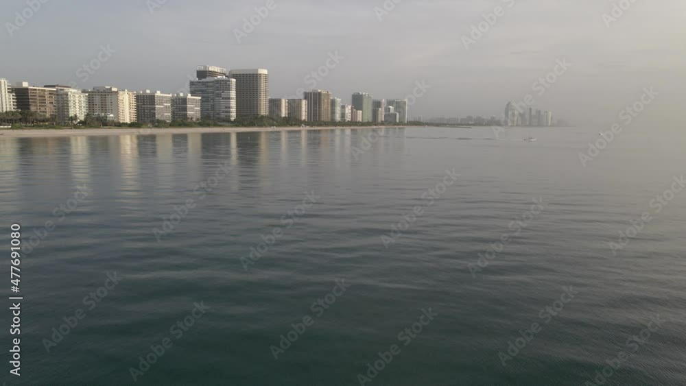 Misty silver sunrise aerial: Condos and calm sea at Surfside, Miami Misty silver sunrise aerial: Condos and calm sea at Surfside, Miami