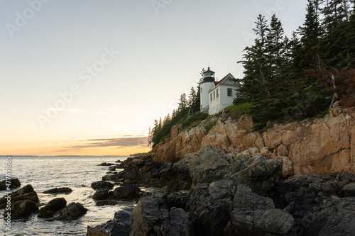 The rocky coast of Maine and the Bass Head Harbor Lighthouse at sunset in summer