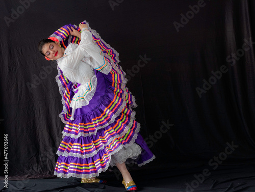 Colombian woman dancing with Tolima Folklore white and purple dress costume with black background and copy space  photo