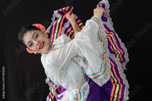 Colombian woman dancing  with Tolima Folklore white and purple dress costume with black background  photo
