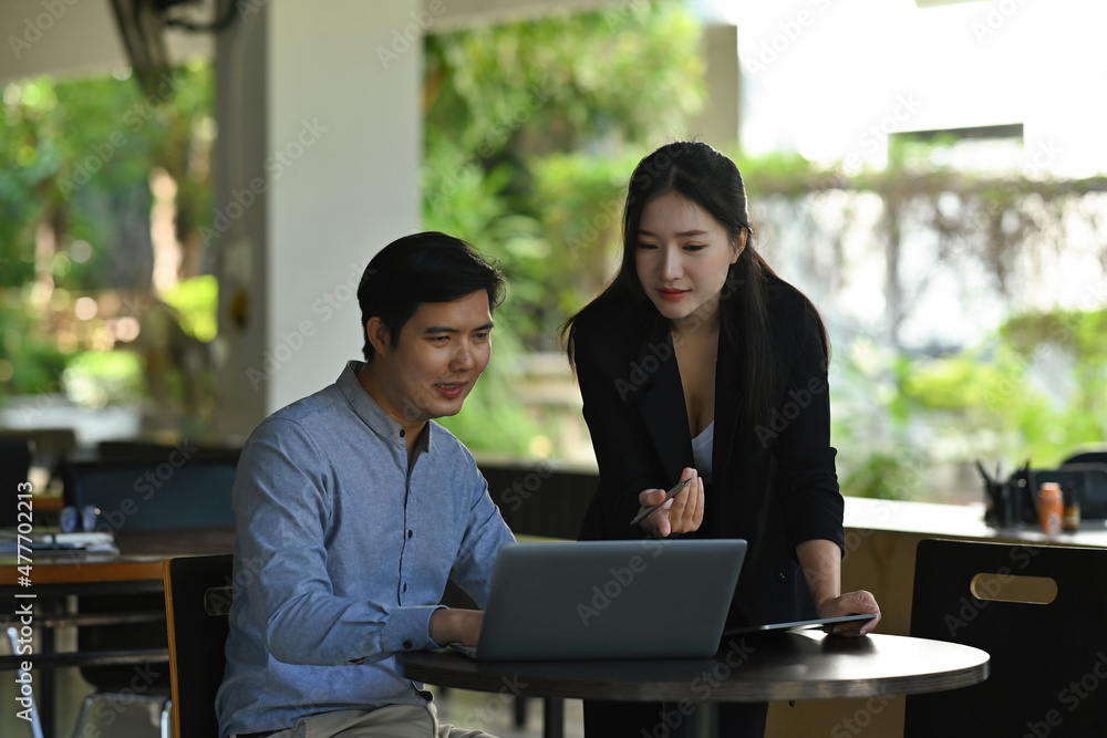 Photo of young businessman and businesswoman focussing on a clipboard at the working desk. Photo of young businessman and businesswoman focussing on a clipboard at the working desk.