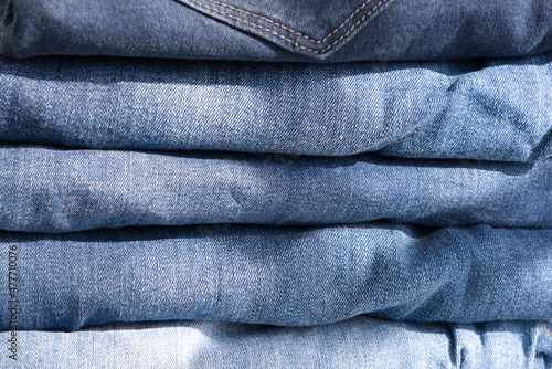 pile of blue jeans on a light background. Close up (ID: 477710076)