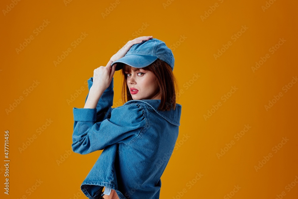 Positive young woman denim clothing fashion posing cap color background unaltered Positive young woman denim clothing fashion posing cap color background unaltered
