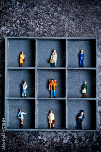 miniature figurines in a box with compartments, concept for pigeonholing and social distancing photo