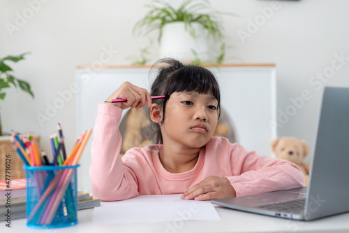 Unhappy little Caucasian girl child sit at table at home feel lazy unmotivated doing homework assignment. Upset distressed small 7s kid prepare school task, learn study with books. Education concept.